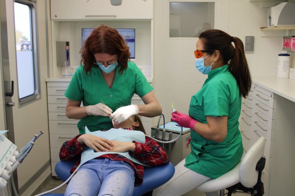 Een tandarts die een kind behandelt in een mobiele tandartspraktijk